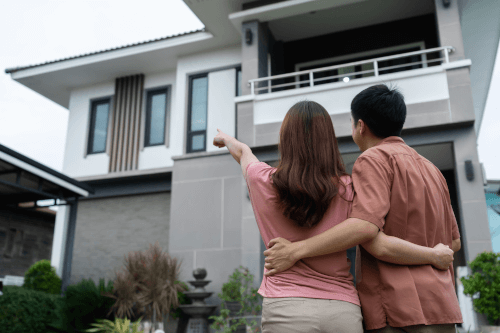 Young-Couple-Standing-Outside-Looking-Their-House A couple and their new house