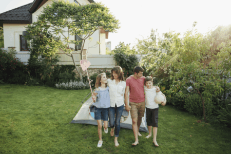 Happy-Family-Walking-Grass-Front-Tent-Outdoors Happy family playing outside