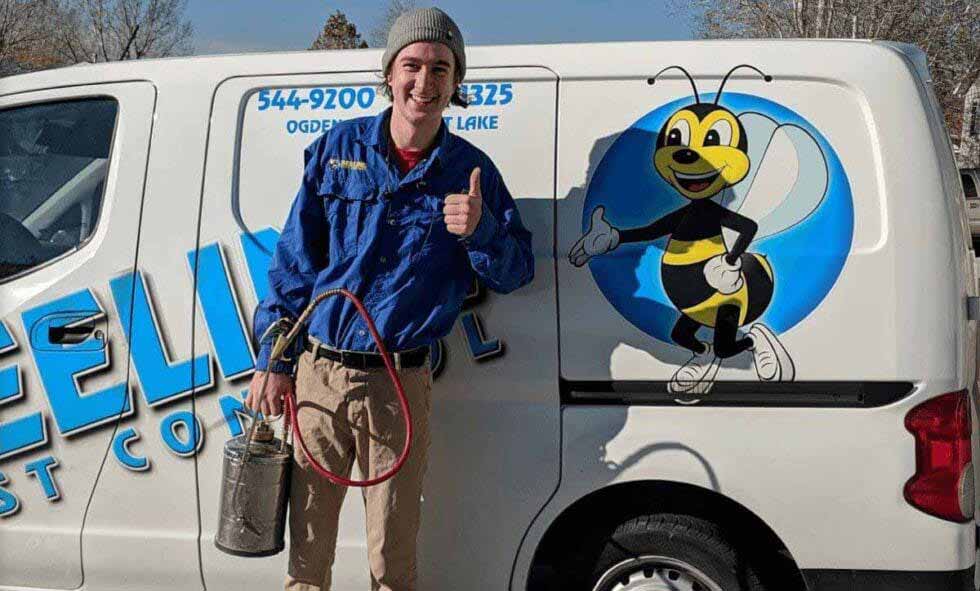 Pest Control Technician From Beeline Smiling pest control worker with equipment gives thumbs-up next to a van with bee mascot.