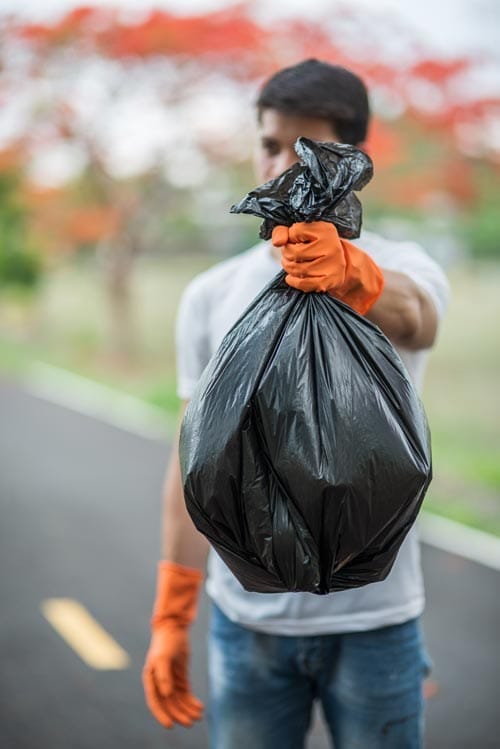 Man collecting garbage black bag