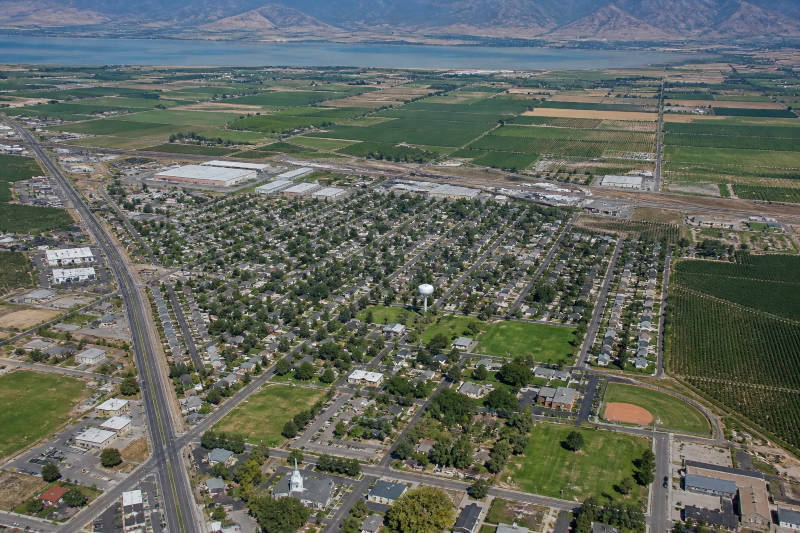 Densely treed residential area, with farms, lake, and mountains in the background.